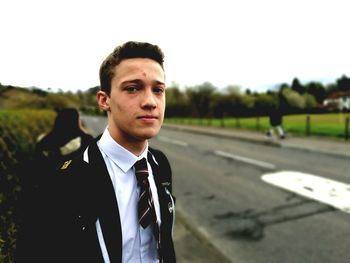 Portrait of teenage school boy standing on footpath