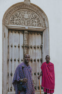 Two masai men standing in front of a traditional door in old town