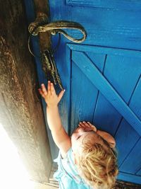 High angle view of cute girl reaching for key hanging on door