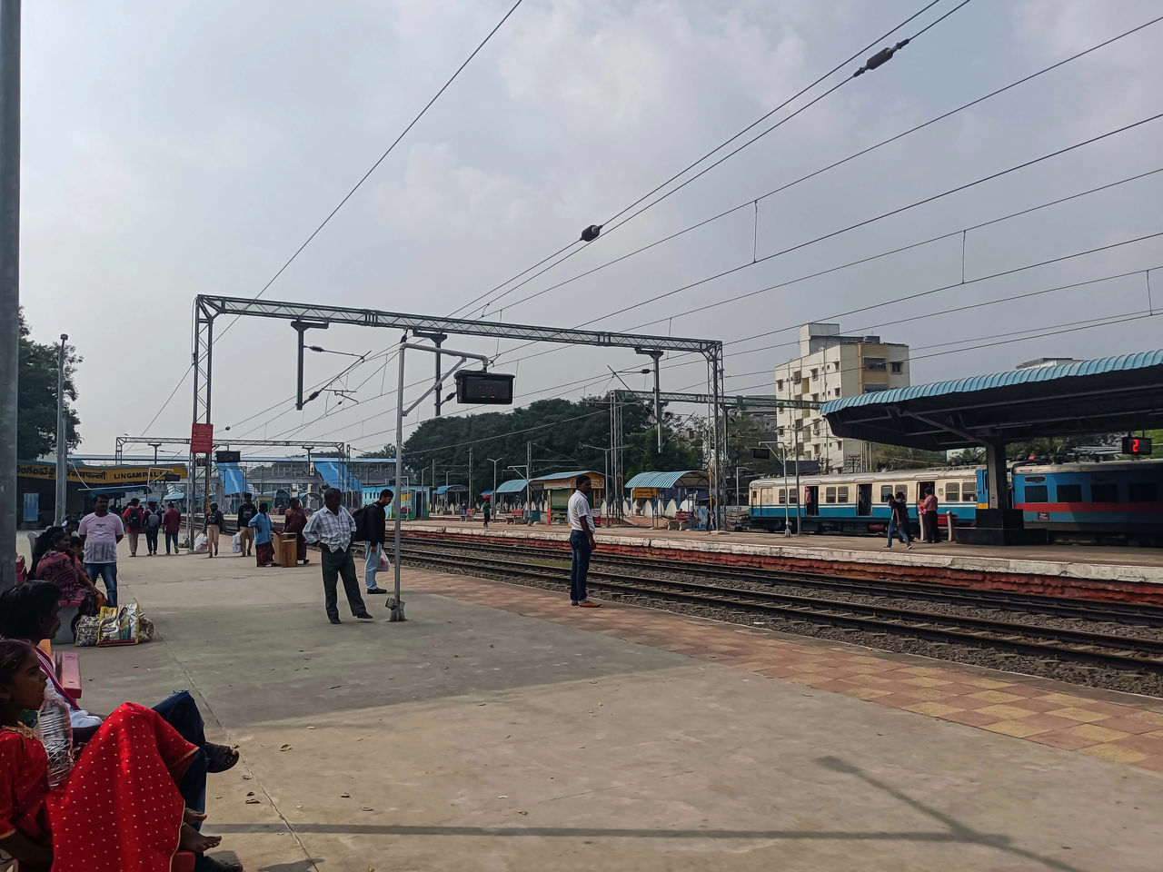 group of people, transport, architecture, sky, transportation, crowd, large group of people, rail transportation, city, mode of transportation, track, railroad track, built structure, nature, travel, cable, men, train, day, vehicle, electricity, train station, building exterior, railroad station, cloud, railroad station platform, outdoors, adult, public transportation, travel destinations, city life, lifestyles, women, power line