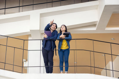 Full length of a smiling young woman standing against wall