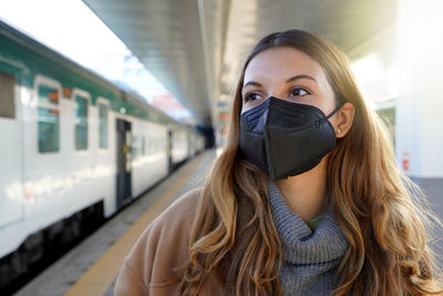 Portrait of young woman wearing a black protective mask kn95 ffp2 on train station
