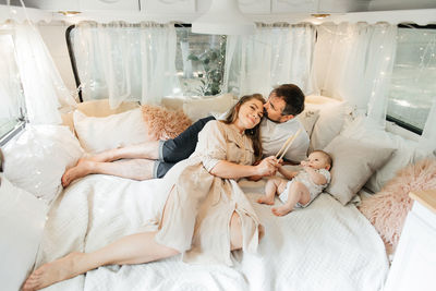 Family with baby on the bed in trailer in the morning. newborn child traveling in camper with