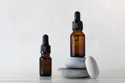 Brown glass bottles with skin oil on stones on a light background.