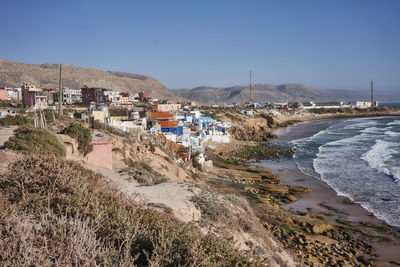 Scenic view of beach by buildings in city against clear sky