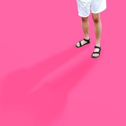 Low section of woman standing against pink background