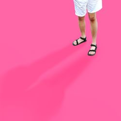 Low section of woman standing against pink background