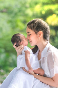 Loving mother holding baby girl while sitting on grass at park