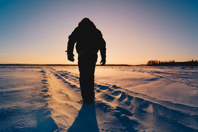 Rear view of silhouette man standing on beach during sunset