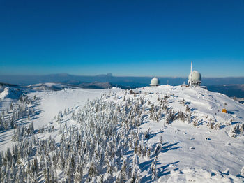 Scenic view of snow covered mountains against blue sky