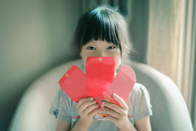 Close-up portrait of girl holding heart shape