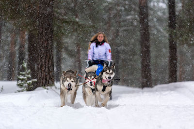 Portrait of woman with dog in snow during winter