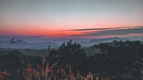 Scenic view of silhouette mountains against orange sky