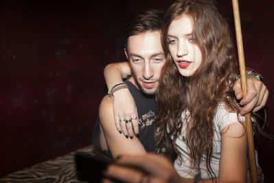 Portrait of smiling young woman using mobile phone at night