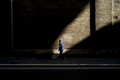 Full length side view of man walking on sidewalk