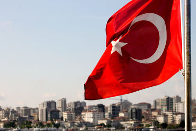 Close-up of flag against buildings in city against sky