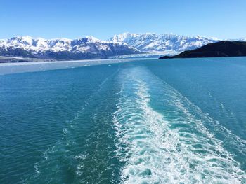 Scenic view of sea and mountains against clear blue sky