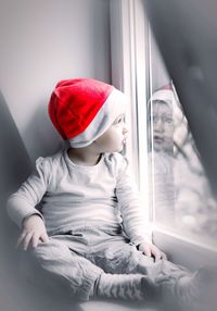 Close-up of cute baby girl sitting on window