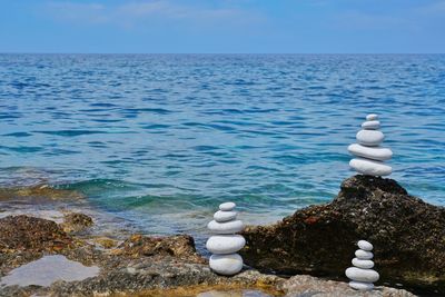 Stack of stones in sea against sky