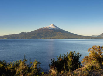 Scenic view of lake and mountains against clear blue sky