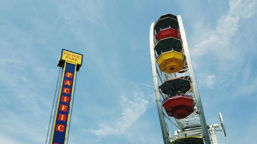 Low angle view of ferris wheel and text against sky