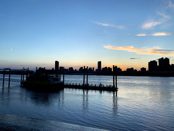 Scenic view of river by buildings against sky during sunset