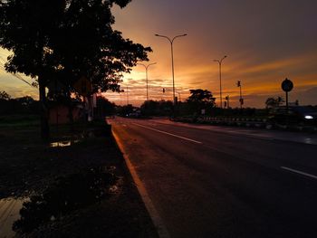 Road by city against sky during sunset