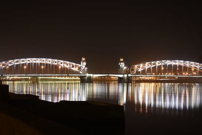 Illuminated bridge over river against sky at night