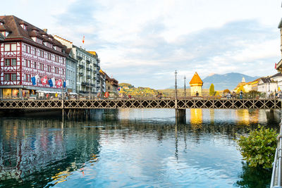 Bridge over river by buildings in city against sky