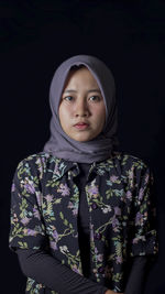 Portrait of woman in hijab against black background