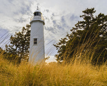 Lighthouse on field against sky