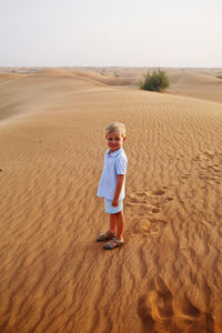 Full length of boy on sand dune in desert