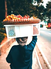 Rear view of woman selling fruits on sidewalk in city