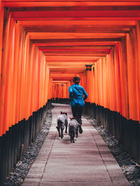 Rear view of man riding boy walking on road