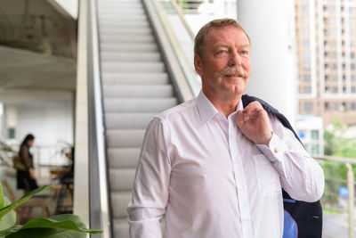 Senior man standing against escalator