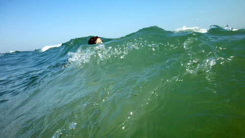 Woman swimming in sea against clear sky