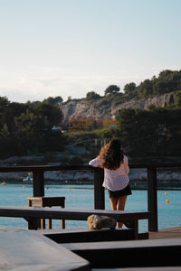 Rear view of woman standing by sea