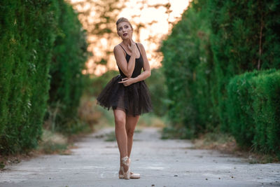 Full length portrait of young woman standing on road