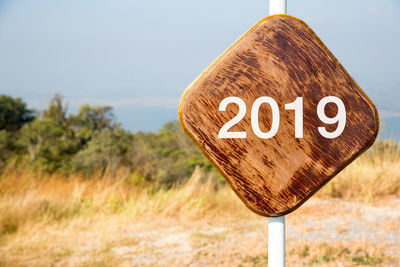 Close-up of road sign on field against sky