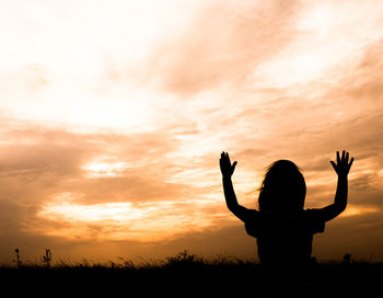 Silhouette woman against orange sky during sunset