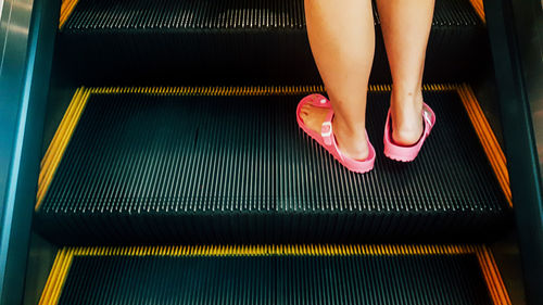 Low section of woman standing on escalator