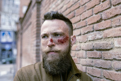 Side view hipster man with beard and cinema makeup posing on the street