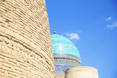 Low angle view of bird on building against sky