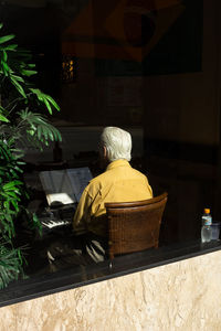 Man wearing yellow shirt and playing piano in restaurant