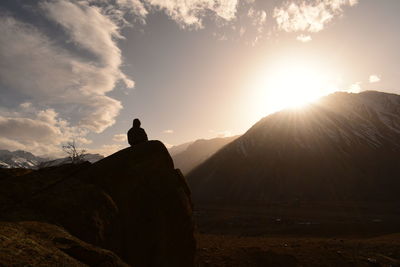 Rear view of man standing on mountain against sky during sunset