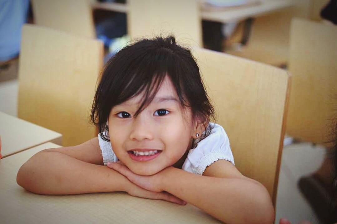 CLOSE-UP PORTRAIT OF SMILING GIRL SITTING ON SOFA