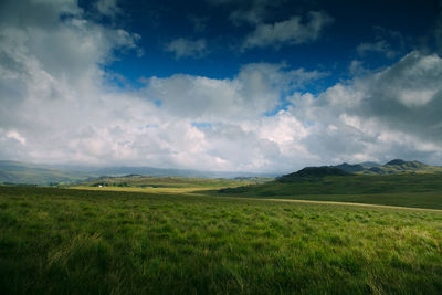 Scenic view of grassy field against cloudy sky