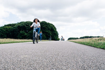 Man with bicycle on road against sky