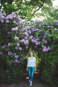 Woman walking against purple flowering plants