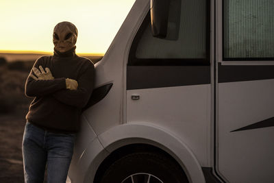 Man wearing mask leaning on van